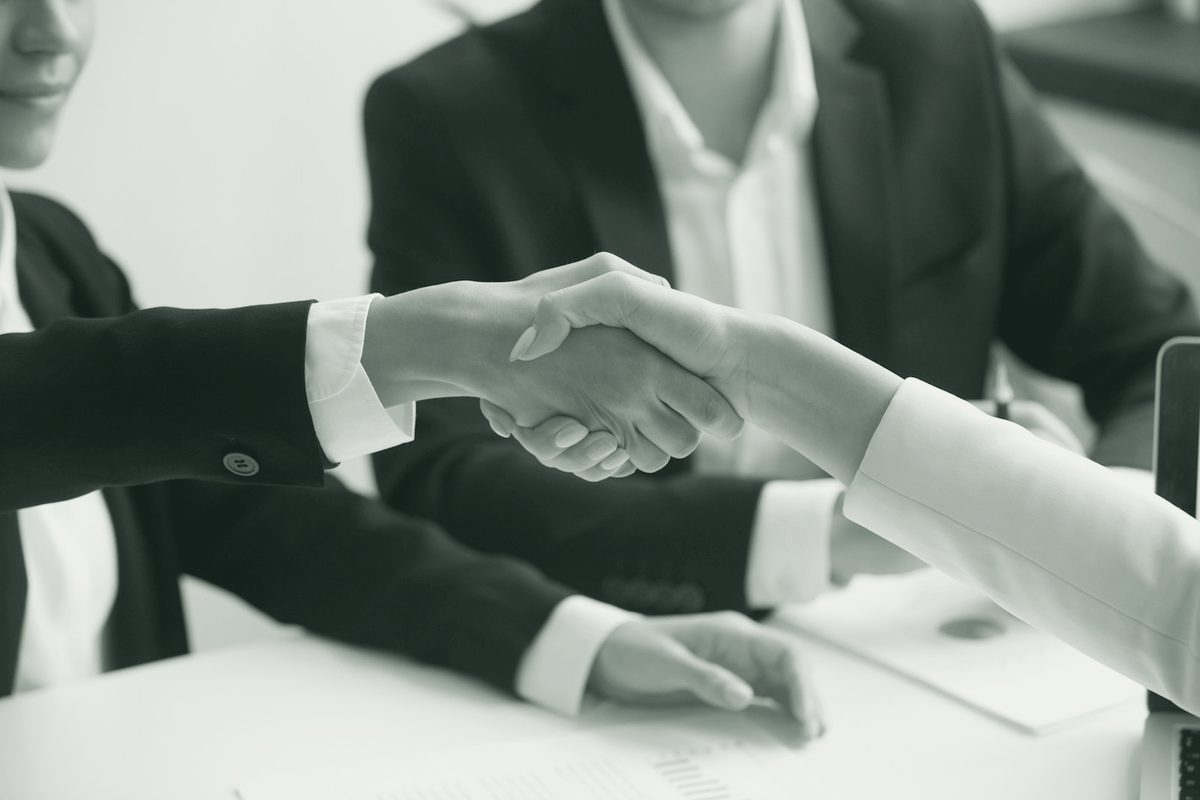 Two people shaking hands across a desk